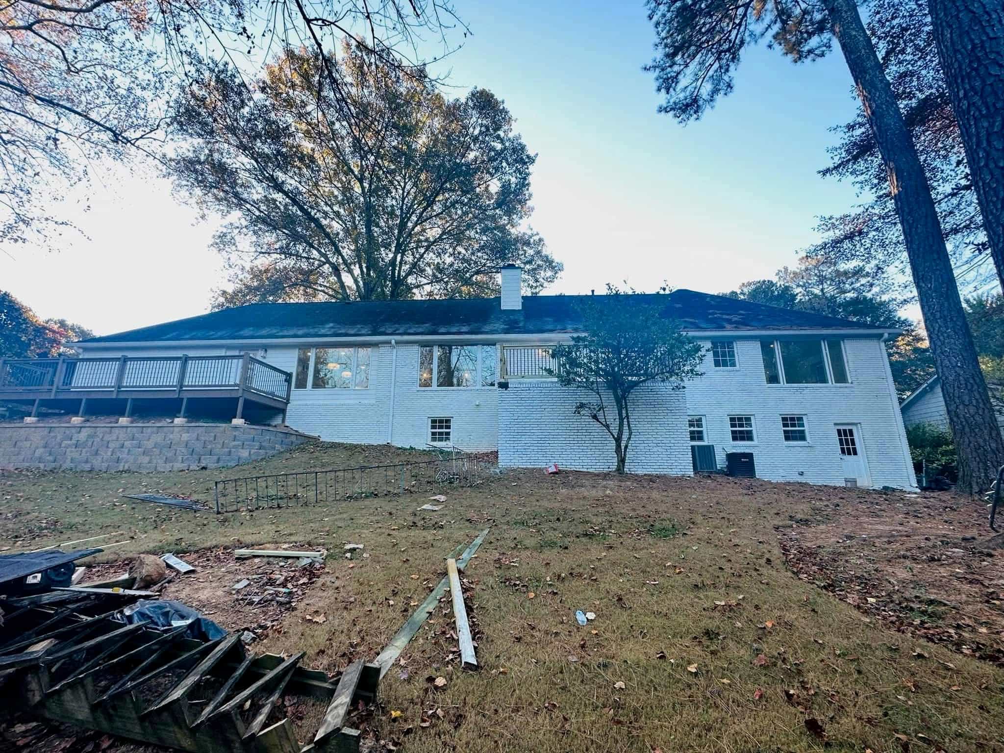 White brick ranch rear view — large back elevation with new gutters and deck