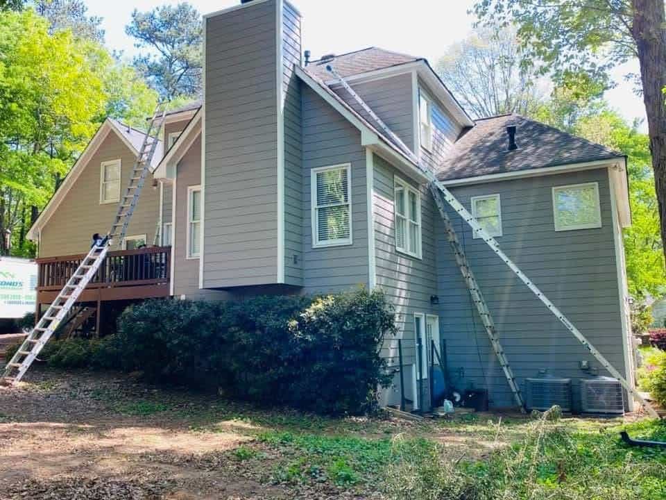 Rear elevation of multi-level home with ladders set for gutter installation