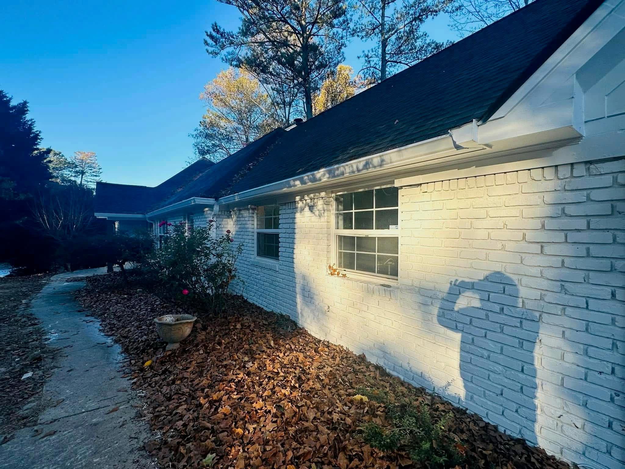 White brick ranch home with new white seamless gutters — side view