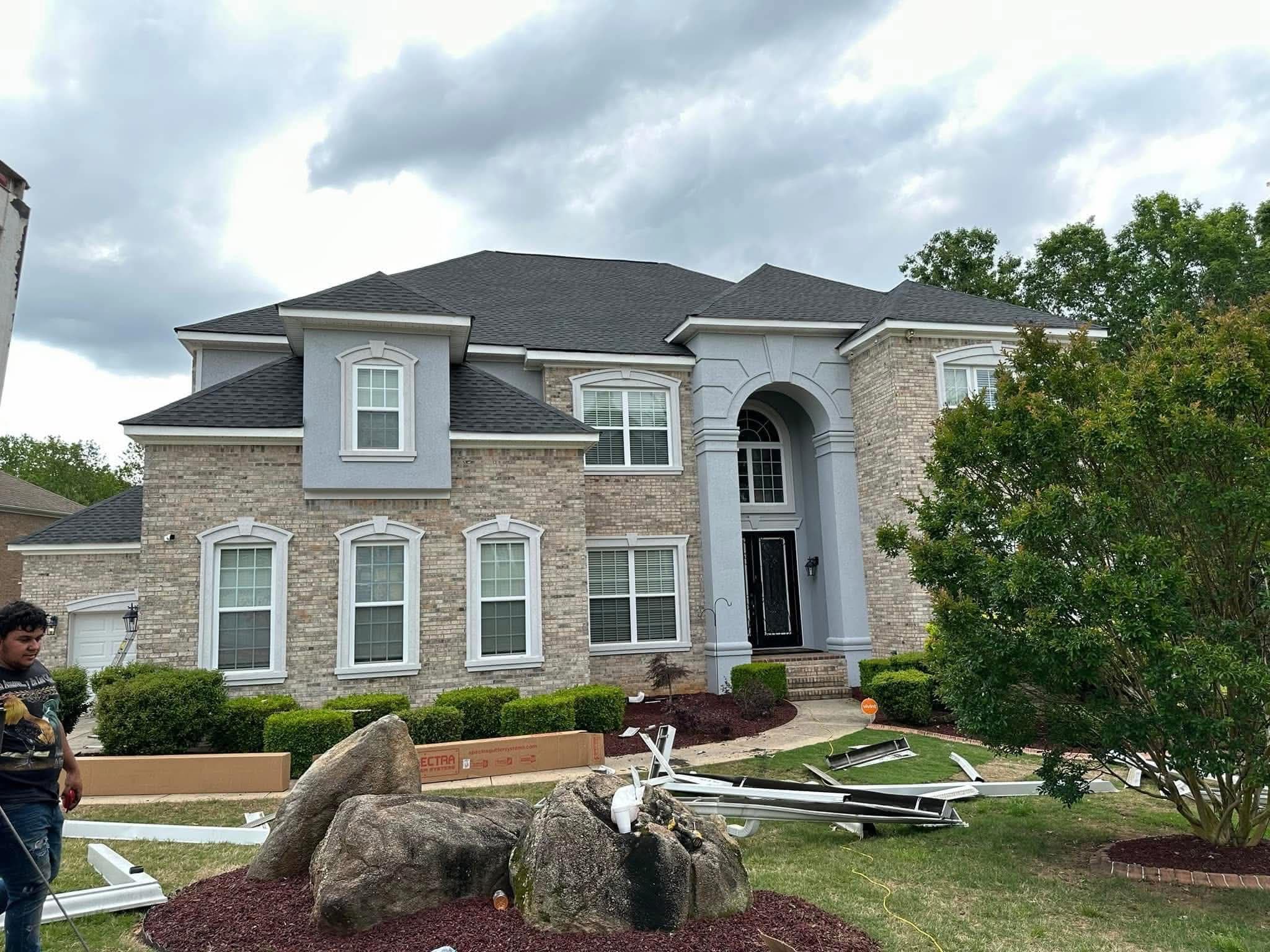 Luxury brick estate — team member with gutter materials ready for installation